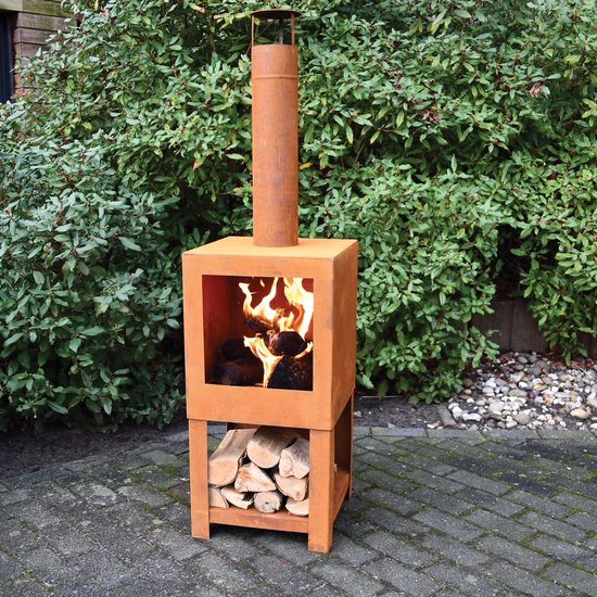 Roestkleurige stalen buitenkachel met brandend haardvuur en houtblokken op de onderste plank, geplaatst op een betegeld terras.