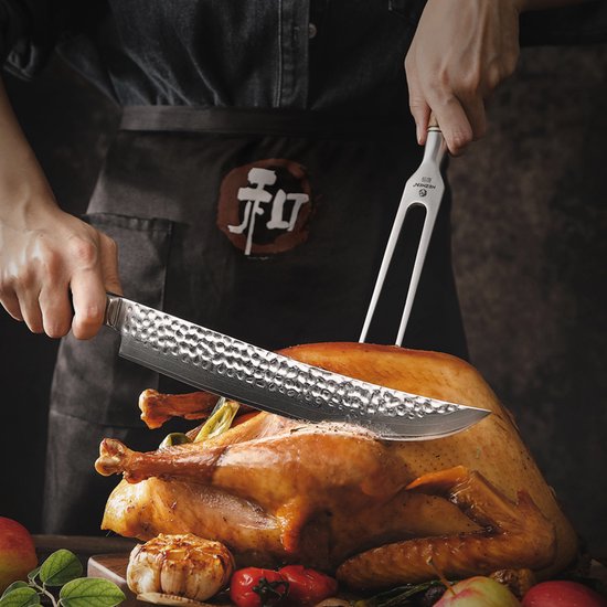 Deux mains utilisent une fourchette à viande pour tenir une dinde rôtie pendant qu'elle est découpée.