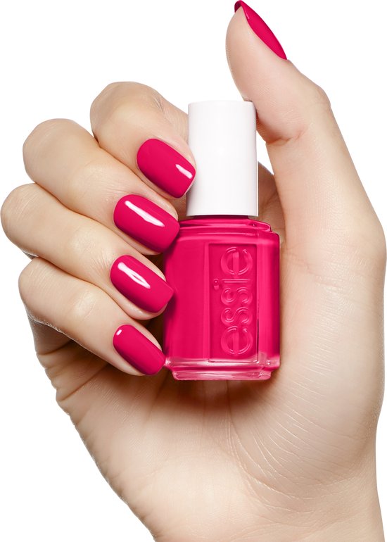 Hand met felroze Essie nagellak, houdt een flesje Essie nagellak vast.