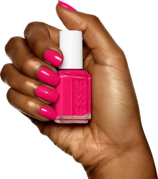 Donkere hand met felroze Essie nagellak, houdt een flesje Essie nagellak vast.