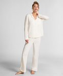 Model staand in een witte jersey pyjamaset met lange mouwen.
