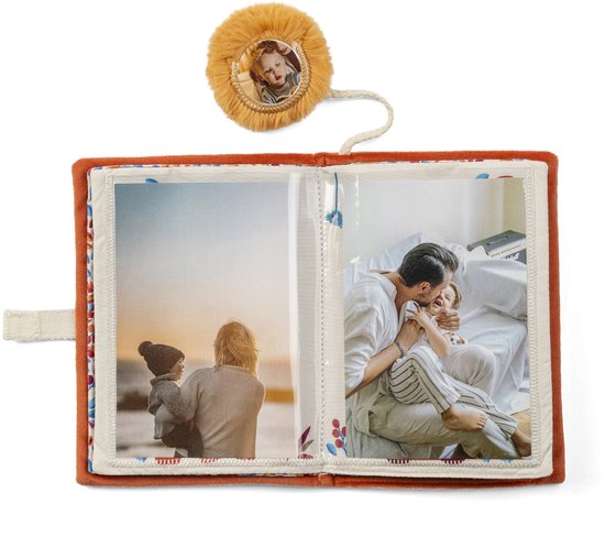 Open stoffen fotoalbum met oranje hoes en twee foto's: kind met rug naar je toe aan zee en vader met kind in bed.