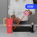 Vrouw demonteert het deksel van een koraalrode Kambukka beker met lichtgeel handvat. Oranje rietje in de hand.