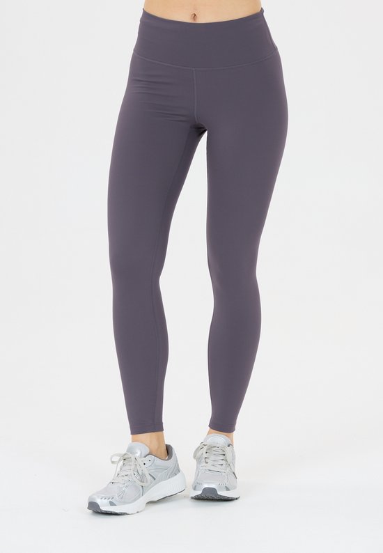 De benen van een vrouw in een grijze legging en sneakers.