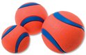 Drie oranje Chuckit! ballen met blauwe strepen in verschillende maten op een witte achtergrond.