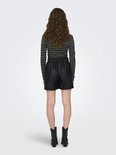 Zicht op de achterkant van een model in zwarte kunstleren shorts met elastische tailleband, gestreepte coltrui en zwarte enkellaarsjes.