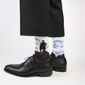 Witte sokken met een man op een rots, uitzicht op bergen, met zwarte schoenen.
