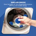 Boules de séchage bleues dans une machine à laver, une main ajoutant 4 boules à une charge de linge.