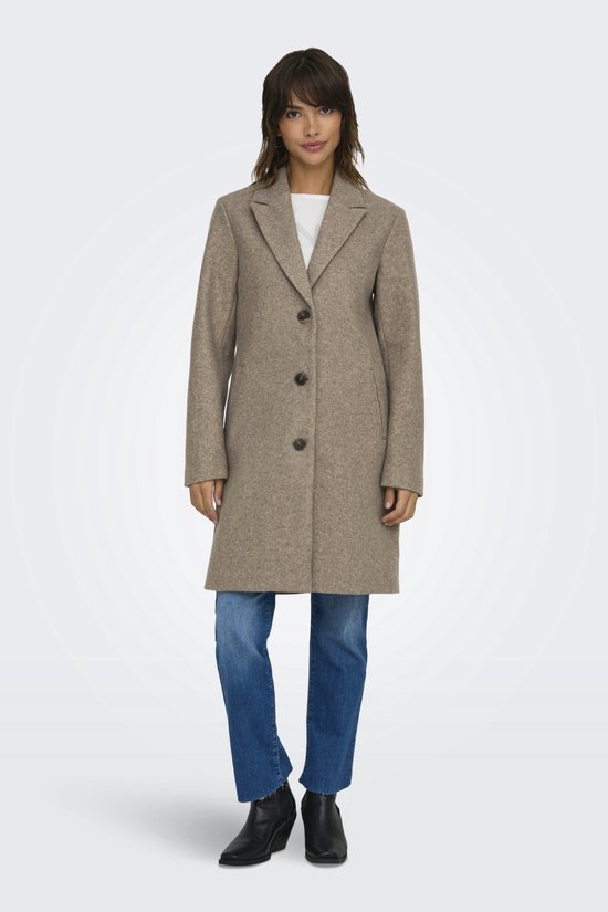 Model in bruine jas, witte top en blauwe jeans.