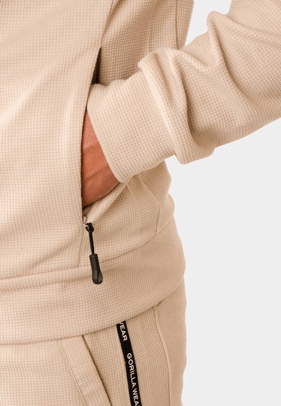 Detail van een beige Gorilla Wear trainingsjack met ritszak.