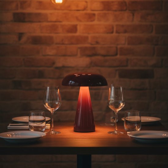 Rode champignon lamp op een gedekte tafel met servies en wijnglazen.