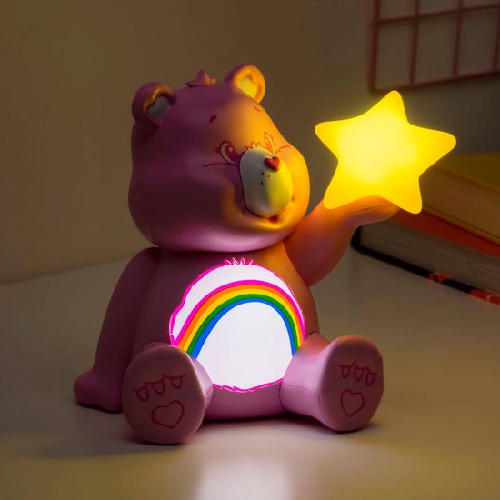 Veilleuse Cheer Bear rose avec un arc-en-ciel lumineux et une étoile jaune, sur un bureau.