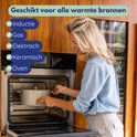 Vrolijke vrouw met blond haar in spijkerblouse zet een pan in een open oven.