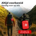 Twee wandelaars met rugzakken in een berglandschap. De rechter rugzak heeft een rode verbanddoos met karabijnsluiting eraan bevestigd.