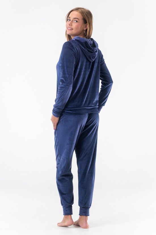 Model draagt een marineblauw velours joggingpak met rits en capuchon, van achteren gezien.