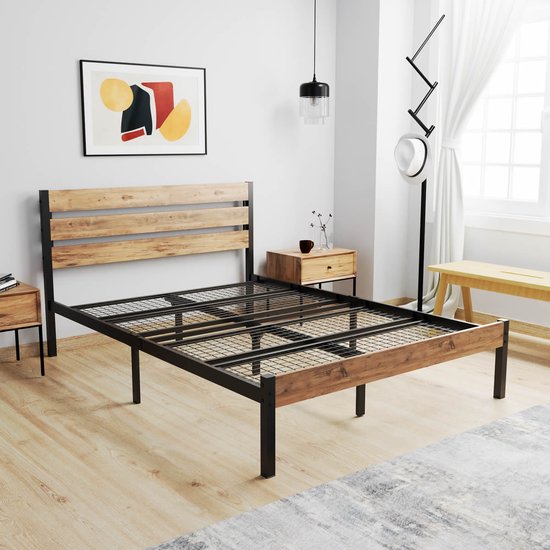 Bedframe met houten hoofdbord, zwart metalen frame, in een lichte slaapkamer met schilderij.