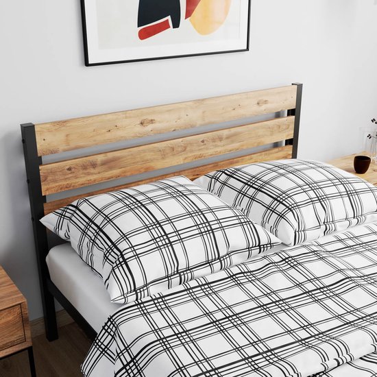 Close-up van houten bedframe met zwart metalen frame en wit/zwart geruite kussens.