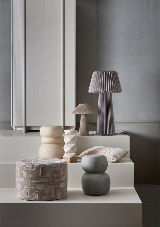 Stapelbare ronde bijzettafels van fiber clay in beige en grijs, naast decoratieve kussens.