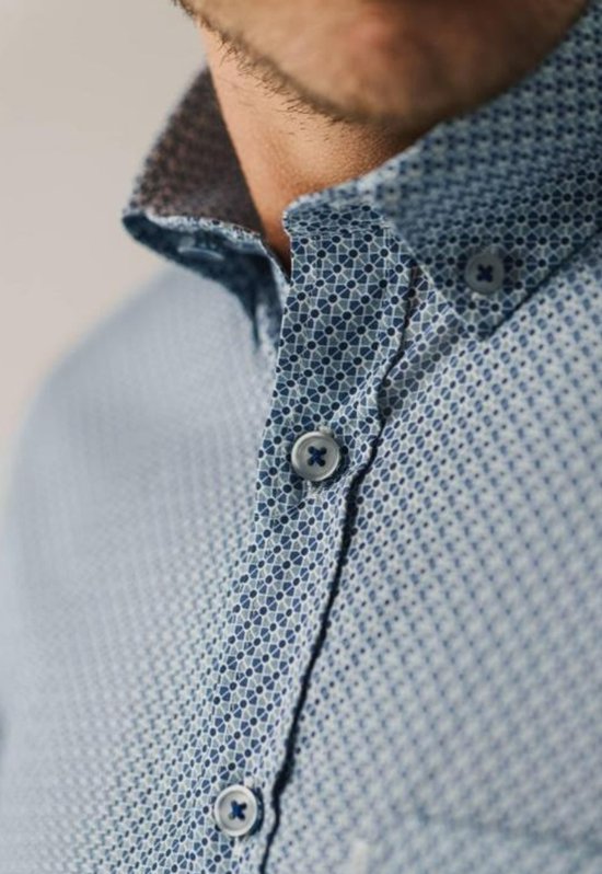 Close-up van kraag en knoopsluiting van een blauw overhemd met geometrische print.