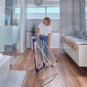 Femme dans une salle de bain moderne tenant un étendard pliable blanc et bleu.