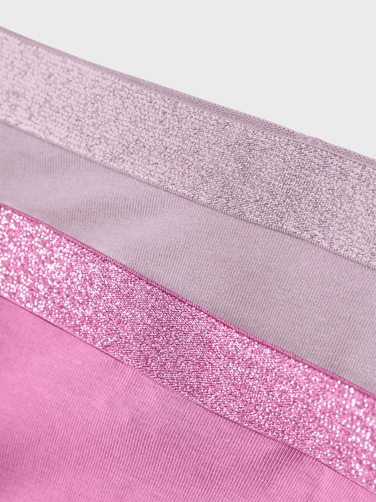 Detail van glitter taillebanden in roze en oudroze op hipsters.