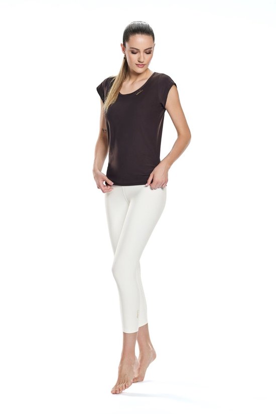 Model draagt een donkerbruin shirt met korte mouwen en een witte driekwart legging.