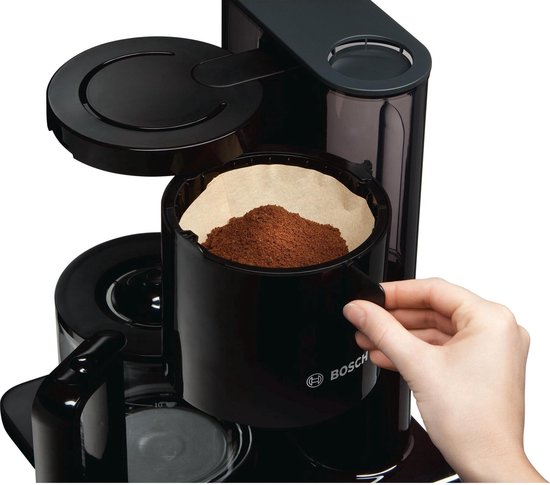 Hand plaatst filter met koffie in zwart Bosch koffiezetapparaat.
