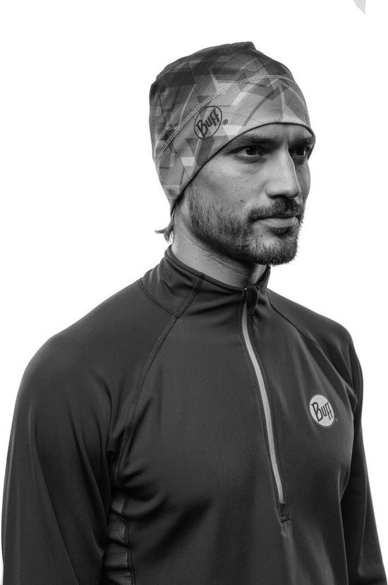 Zwart-wit portret van een man met muts met geometrisch patroon en een vest met rits.