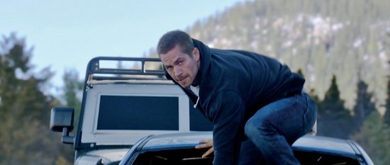 Een man in een donkerblauwe hoodie en spijkerbroek klimt op een pick-up truck.