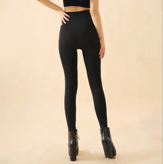 Een model draagt een zwarte legging met hoge taille en zwarte plateau laarzen met veters. Achteraanzicht.