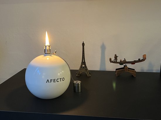 Witte Afecto olielamp met vlam, metalen ketting met dop, naast Eiffeltoren model.