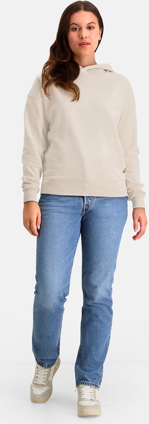 Vrouw draagt een ecru hoodie met gele applicatie en jeans.