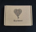 Bruine kartonnen geschenkdoos met daarop een zwart hartvormig sleutel-logo en 'KeyAmor' in sierlijke letters.