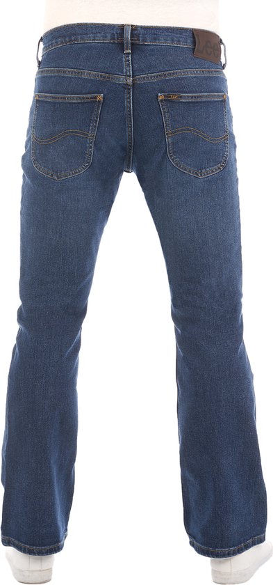 Man in een blauwe bootcut jeans van Lee, achterkant met witte sneakers.