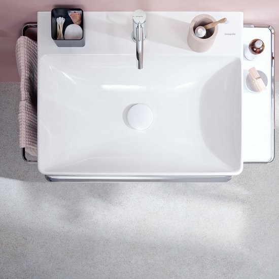 Chromen wastafelkraan op een rechthoekig witte wastafel, met accessoires ernaast.