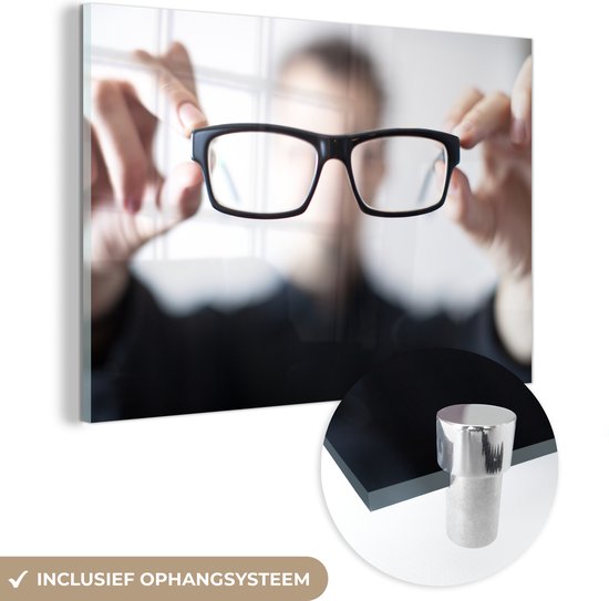 MuchoWow® Glasschilderij 180x120 cm - Schilderij acrylglas - Een close-up man met bril die de bril toont aan de camera. - Foto op glas - Schilderijen