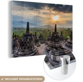 MuchoWow® Glasschilderij 150x100 cm - Schilderij acrylglas - Zonsondergang boven de groene bomen bij de Borobudur - Foto op glas - Schilderijen