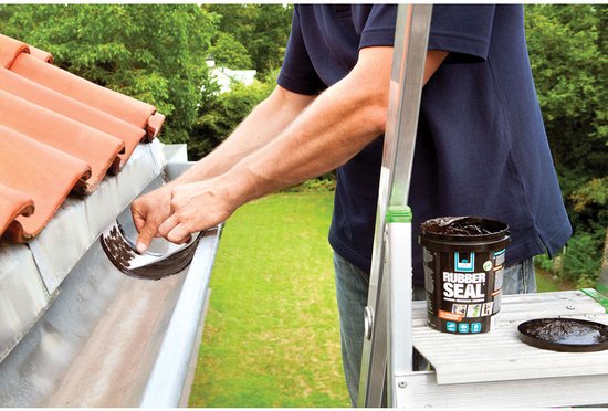 Hand reinigt een dakgoot waarin donkerbruine coating zit, naast een pot Rubber Seal.