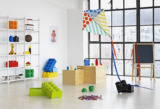 Salle de jeux avec des boîtes de rangement LEGO, y compris une verte au sol, et un grand cerf-volant multicolore.