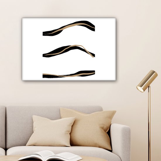 Abstract schilderij met drie zwarte en goudkleurige lijnen boven een grijze bank met kussens.