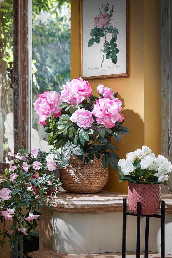 Pivoines roses et fleurs blanches dans des paniers en rotin, à côté d'un tableau.