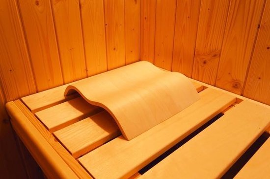 Een lichte houten sauna hoofdsteun met golvend ontwerp op een houten bankje in een sauna.