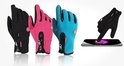 Zwarte, roze en blauwe winterhandschoenen, één hand raakt smartphone aan.