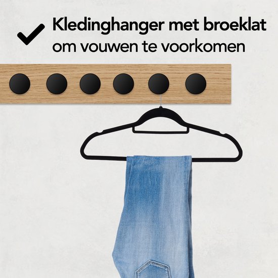 Zwarte kledinghanger met broeklat voor het voorkomen van vouwen, met spijkerbroek.