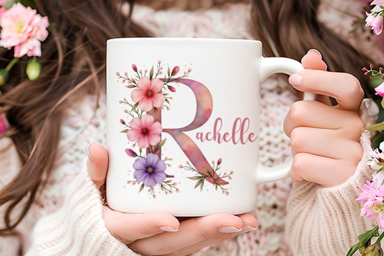Witte mok met grote paarse letter R en de naam 'Rachelle', versierd met bloemen.