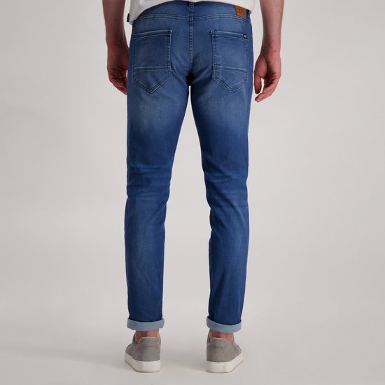 Blauwe spijkerbroek, slim fit, met omgeslagen broekspijpen, gedragen door een model.
