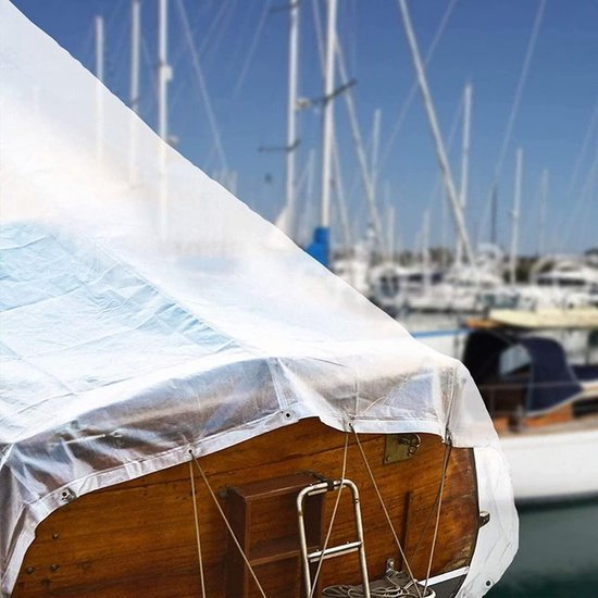 Bâche transparente couvrant un bateau en bois, avec vue sur des bateaux dans un port en arrière-plan.