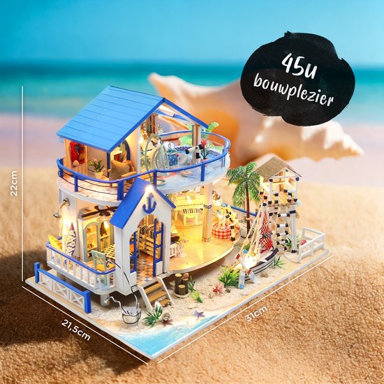 Miniatuur strandhuis met blauw dak, balkon en boot. Afmetingen 31x21,5x22cm. Geplaatst op een strand met schelp.