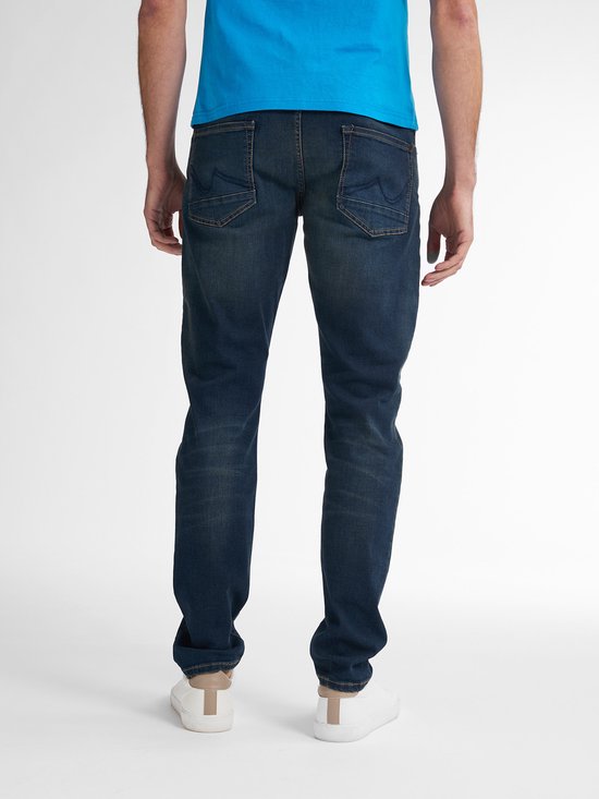 Achterkant van een man in blauw t-shirt en spijkerbroek met twee achterzakken.
