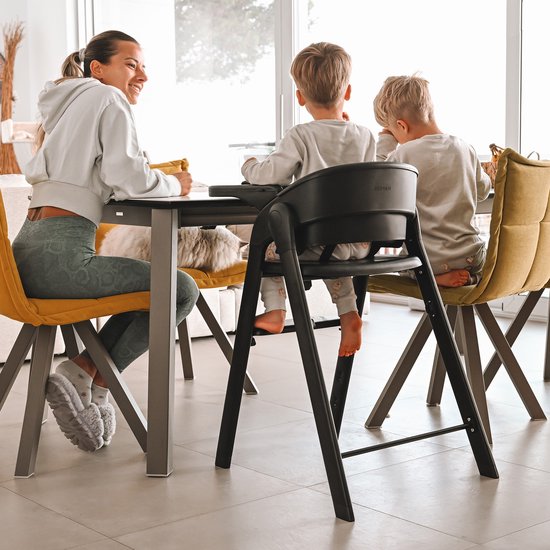Zwarte Deryan kinderstoel met een vrouw en twee kinderen aan tafel.